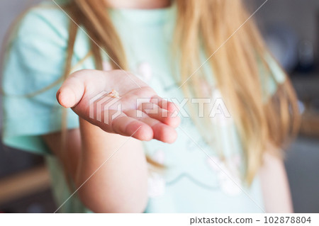Little girl's hand holding and showing her fallen milk front tooth close up. Little girl's hand holding and showing her fallen milk front tooth close up. 102878804