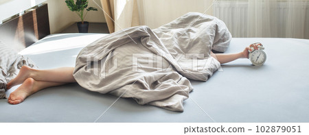 boy lying on bed and stopping alarm clock in morning. childs hand reaching for alarm clock 102879051