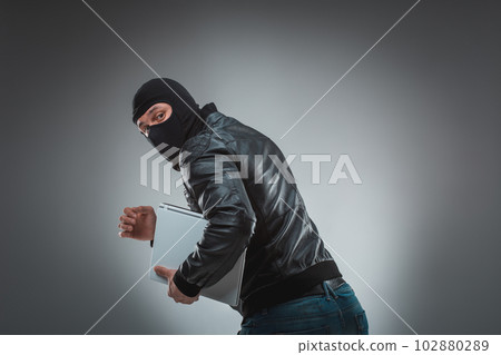 Thief stealing a laptop computer. Isolated on gray background 102880289