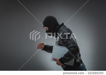 Thief stealing a laptop computer. Isolated on gray background 102880293