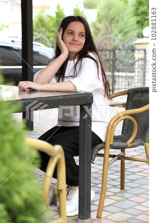 A beautiful teenage girl sits at a table in a cafe. A teenage girl is bored at a table in a cafe. A girl sits at the table. A beautiful teenage girl sits at a table in a cafe. A teenage girl is bored at a table in a cafe. A girl sits at the table. 102881163