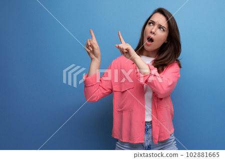 shocked black haired lady in casual style pointing finger at wall in studio background shocked black haired lady in casual style pointing finger at wall in studio background 102881665