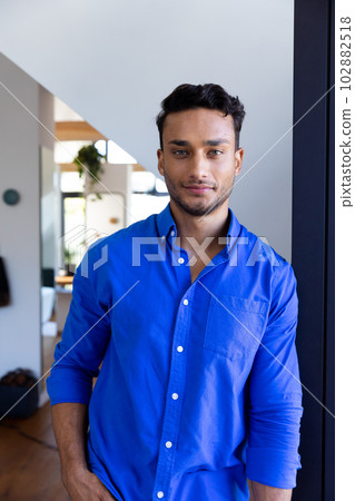 Portrait of happy biracial man leaning on window and looking at camera Portrait of happy biracial man leaning on window and looking at camera 102882518