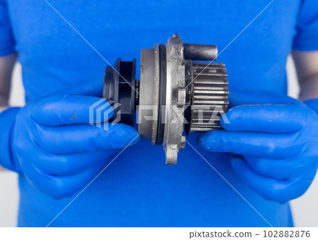 Timing belt cracked. Replacing a failed engine transmission belt. Cracks in rubber and risk of broken cords. Replacement of equipment according to the regulations. Mechanic in blue gloves Timing belt cracked. Replacing a failed engine transmission belt. Cracks in rubber and risk of broken cords. Replacement of equipment according to the regulations. Mechanic in blue gloves 102882876