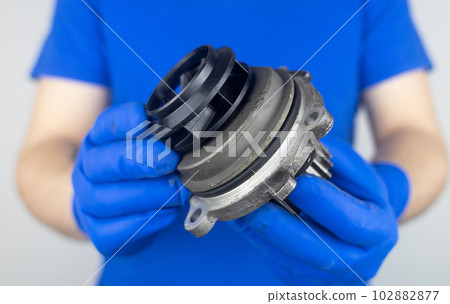 Timing belt cracked. Replacing a failed engine transmission belt. Cracks in rubber and risk of broken cords. Replacement of equipment according to the regulations. Mechanic in blue gloves 102882877