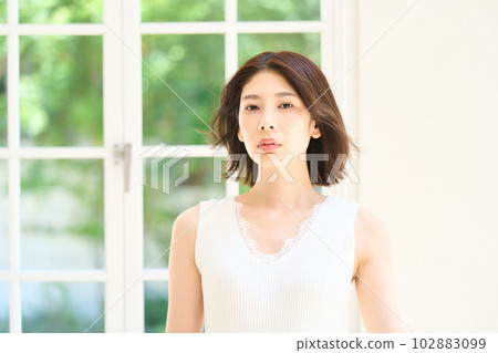 Young woman basking in the sun by the window Young woman basking in the sun by the window 102883099