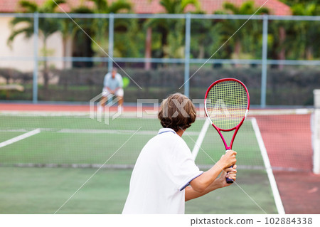 Child playing tennis on outdoor court 102884338