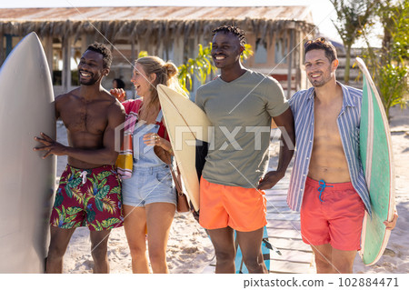 Happy diverse friends holding surfboards at beach Happy diverse friends holding surfboards at beach 102884471