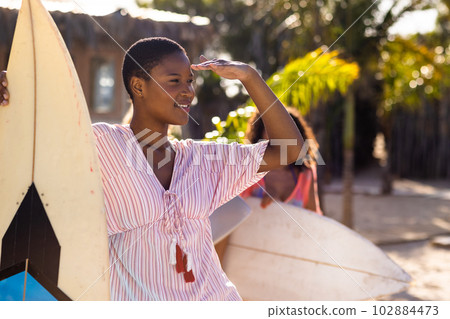Happy diverse female friends holding surfboards at beach Happy diverse female friends holding surfboards at beach 102884473