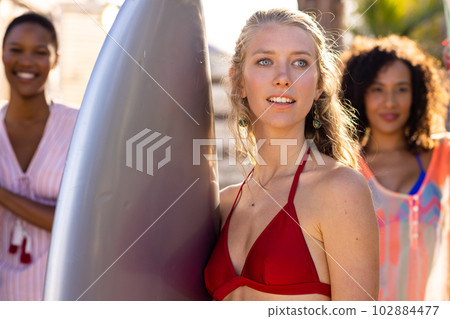 Happy diverse female friends holding surfboards at beach 102884477