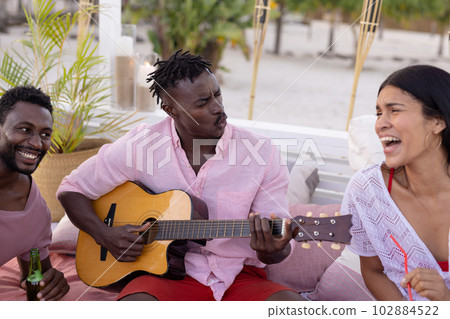 Happy diverse friends having party by swimming pool, playing guitar and singing 102884522