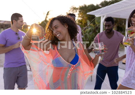 Happy diverse friends having party by swimming pool, holding cocktails and dancing 102884523