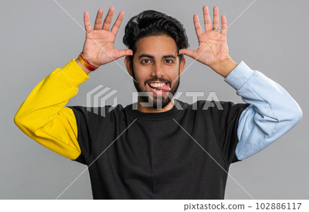 Comical funny indian man making playful silly facial expressions, fooling around, showing tongue Comical funny indian man making playful silly facial expressions, fooling around, showing tongue 102886117