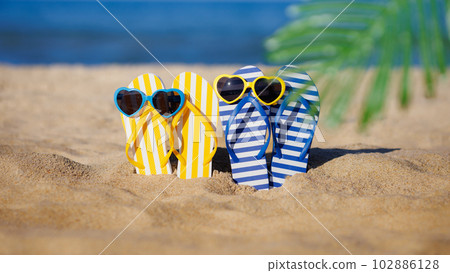 Flip-flops and sunglasses on the sand. Summer vacation concept Flip-flops and sunglasses on the sand. Summer vacation concept 102886128