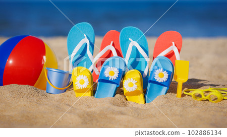 Family flip-flops, beach ball and snorkel on the sand. Summer vacation concept Family flip-flops, beach ball and snorkel on the sand. Summer vacation concept 102886134