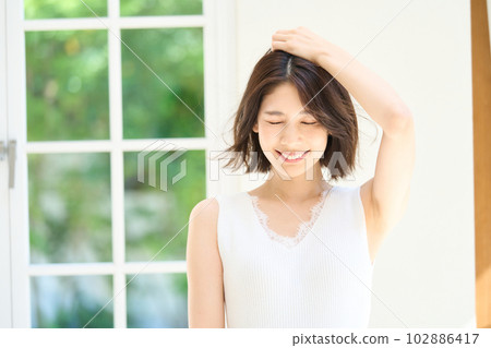 Young woman basking in the sun by the window Young woman basking in the sun by the window 102886417