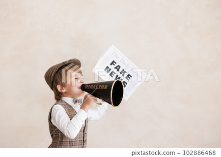 Newsboy shouting against grunge wall background. Boy selling fake news 102886468