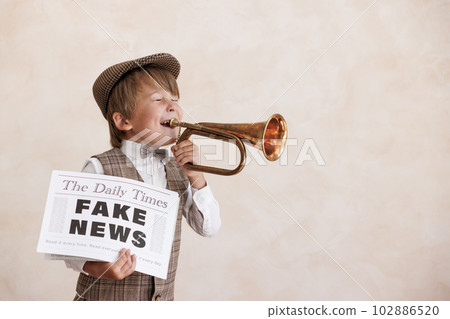 Newsboy shouting against grunge wall background. Boy selling fake news Newsboy shouting against grunge wall background. Boy selling fake news 102886520