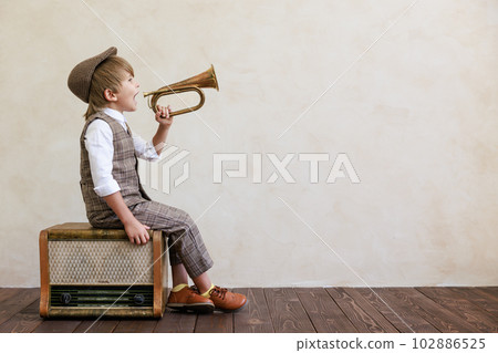 Newsboy shouting against grunge wall background. Boy selling newspaper 102886525