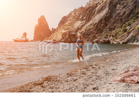 Fitness woman sea. Happy middle-aged woman in blue sportswear running on the beach, promoting a female fitness pilates yoga routine concept. Healthy lifestyle. 102886661