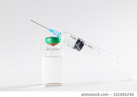 Vial of clear liquid and large syringe on white background 102888298