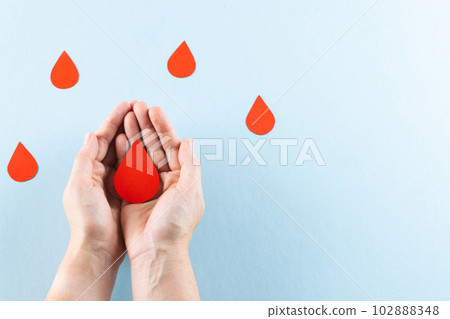 Hands of caucasian woman cupping blood drop, with blood drops on blue background, copy space Hands of caucasian woman cupping blood drop, with blood drops on blue background, copy space 102888348