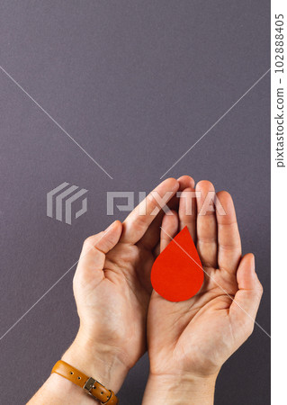 Hands of caucasian woman cupping blood drop, on grey background with copy space Hands of caucasian woman cupping blood drop, on grey background with copy space 102888405