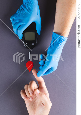 Hands of gloved doctor with glucometer taking blood sugar reading from caucasian woman Hands of gloved doctor with glucometer taking blood sugar reading from caucasian woman 102888409