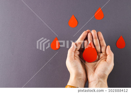 Hands of caucasian woman cupping blood drop, with blood drops on grey background, copy space Hands of caucasian woman cupping blood drop, with blood drops on grey background, copy space 102888412