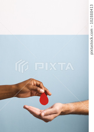 Hands of biracial man giving blood drop to caucasian man, on blue and white background, copy space Hands of biracial man giving blood drop to caucasian man, on blue and white background, copy space 102888413