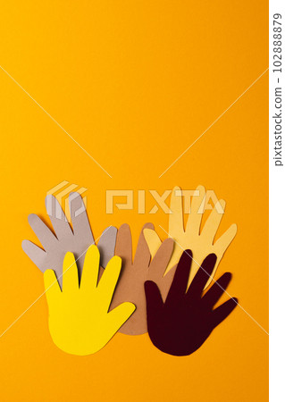 Close up of paper cut out of multi coloured hands with copy space on orange background Close up of paper cut out of multi coloured hands with copy space on orange background 102888879