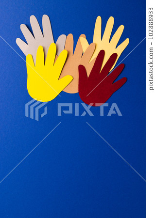 Close up of paper cut out of multi coloured hands with copy space on blue background 102888933