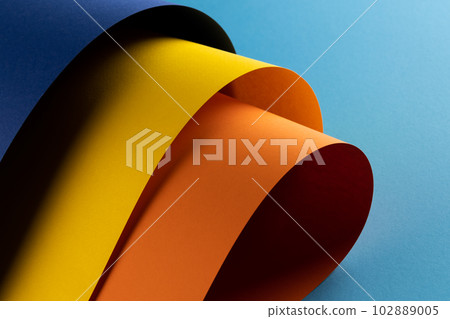 Close up of navy blue, yellow and orange paper on blue background 102889005