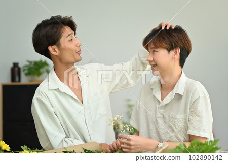 Shot of romantic asian man giving a bunch of flowers to his boyfriend. LGBTQ people lifestyle and love emotion 102890142