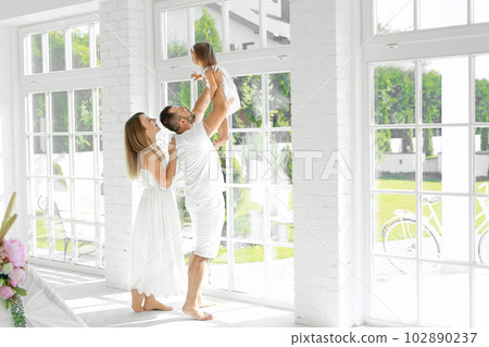 A happy family with a small child in their new apartment overlooking the courtyard.  The father lifts his daughter in his arms in front of him 102890237