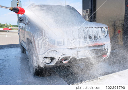 Car wash with soap from a hose in the open air. Car in foam 102891790