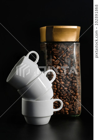 White coffee cups and a jar of coffee on a black background 102891868