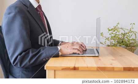 Image of a businessman typing on a computer with correct posture Image of a businessman typing on a computer with correct posture 102894172