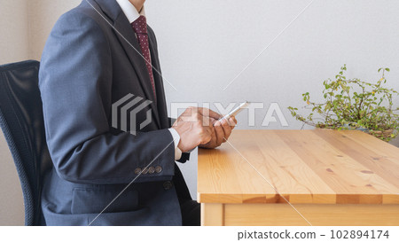 A businessman who operates a smartphone with the correct posture A businessman who operates a smartphone with the correct posture 102894174