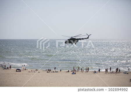 Ukraine. Odessa region. Zatoka, August 30, 2019. Military helicopter flies over the beach with vacationers Ukraine. Odessa region. Zatoka, August 30, 2019. Military helicopter flies over the beach with vacationers 102894992