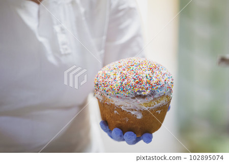 Hands decorate Easter bun. Professional baking Easter cakes. 102895074