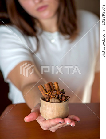 Hands of young woman holding wooden cup with spices 102895978
