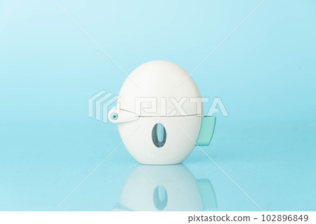 Asthma and COPD concept. Tiotropium bromide inhaler with reflection on light blue background. Pharmaceutical device of bronchodilator for lung inflammation treatment and prevent asthma attack. Asthma and COPD concept. Tiotropium bromide inhaler with reflection on light blue background. Pharmaceutical device of bronchodilator for lung inflammation treatment and prevent asthma attack. 102896849