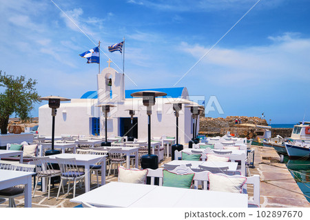 Outdoor dining by waterfront, fishing boat harbour of Naoussa, Paros island, Greece. Outdoor dining by waterfront, fishing boat harbour of Naoussa, Paros island, Greece. 102897670