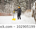 A man in the backyard is clearing the street from deep heavy snow 102905199