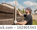 Man builds sections of fence around his yard out of planks 102905343