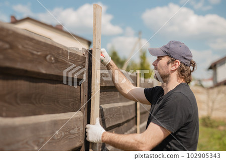 Man builds sections of fence around his yard out of planks Man builds sections of fence around his yard out of planks 102905343