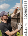 Man builds sections of fence around his yard out of planks 102905345