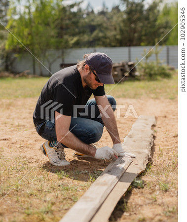 Man builds sections of fence around his yard out of planks Man builds sections of fence around his yard out of planks 102905346