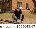 An adult man is engaged in carpentry work at a house construction site 102905347